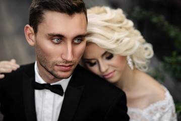 Sensual charming bride gently put her head on the shoulder of her handsome courageous groom