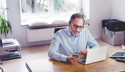 Grey Bearded mature man creative director sitting in modern office