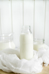 Fresh milk in glass bottles on a light wooden background