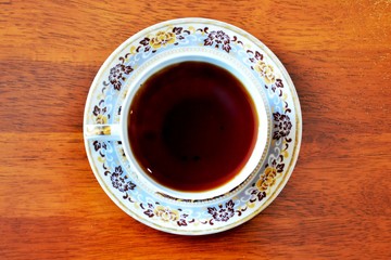 Cup of black tea on wooden table, top view