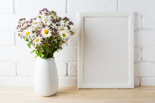 White frame mockup with blooming wildflower bouquet near painted brick wall