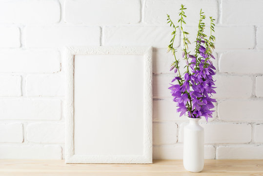 White frame mockup with purple campanula bouquet near brick wall