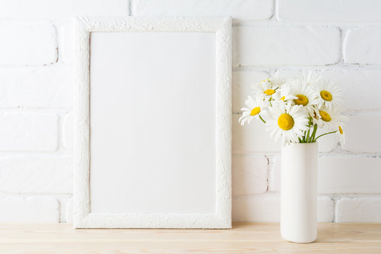 White frame mockup with daisy flower near painted brick wall