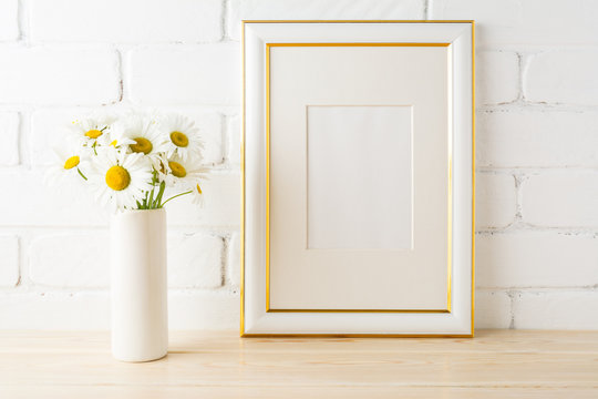 Gold decorated frame mockup with daisy near painted brick wall