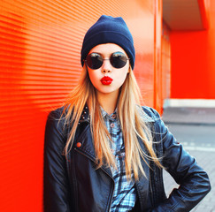 Fashion portrait beautiful blonde woman blowing red lips making air kiss in rock black style