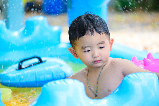 Asian Kid Playing In Inflatable Baby Swimming Pool On Hot Summer Day.