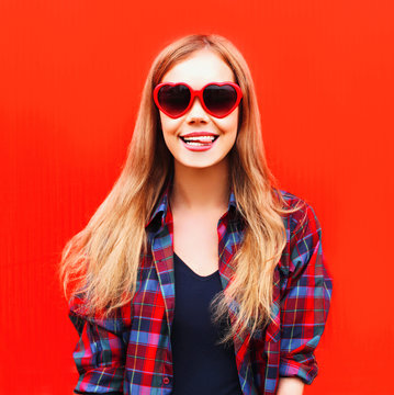 Portrait happy pretty young woman in red sunglasses shape of heart
