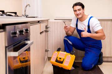 Young repairman working at the kitchen