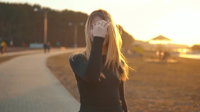Smiling Blond Girl is Walking on Field at Sunset