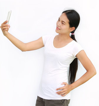 Asian girl taking pictures of herself through cell phone on white background