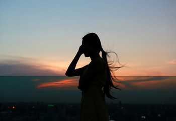 Silhouette of woman relax at sunset on rooftop of the building