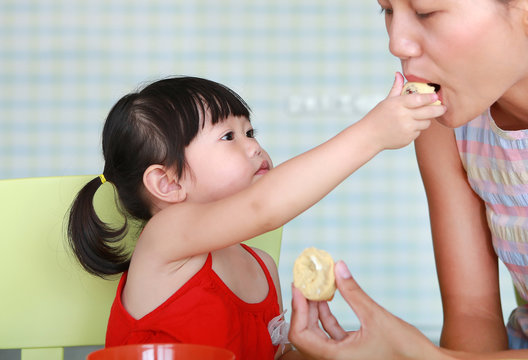 Asian Child girl and mother eating boiled egg at living room