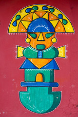 Stylized Maya graffiti on red wall in Banos, Ecuador
