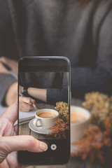 Taking a photo by Finger Pressing on Smartphone for Photograph Close up  Other Hot Coffee on wooden in Social and Meeting. Image for Coffee Advertise or Social Media with Drink Concept