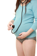 聴診器を自分のお腹にあてる臨月の妊婦