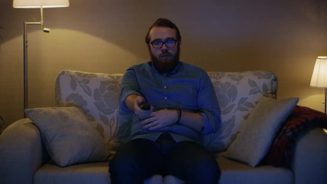 Portrait Shot of a Man Sitting on a Sofa in His Living Room, Watching TV. Shot on RED EPIC-W 8K Helium Cinema Camera.