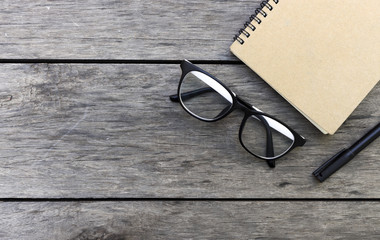 glasses and book on wooden table with soft-focus in the background. over light