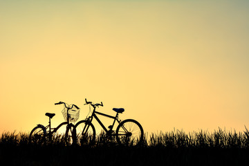 Fototapeta premium Silhouette of bicycle on grass with the sky sunset