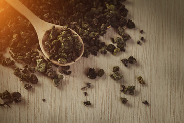 Dry tea in wood spoon on old wood background in flare light