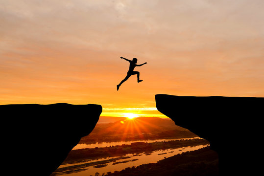 Courage man jumping over cliff on sunset background,Business concept idea