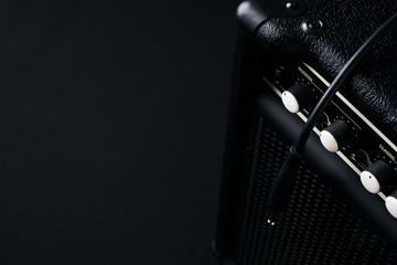 Close up of Black guitar amplifier with jack cable on black background.