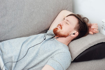 man with beard listening to player and resting