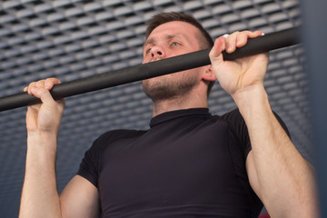 A young man doing pull ups in the Gym