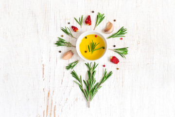 Olive oil, rosemary and spices. Herbs and spices are laid out in the shape of a flower.