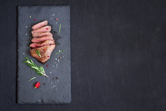 Roast beef steak on slate cutting board, top view with copy space