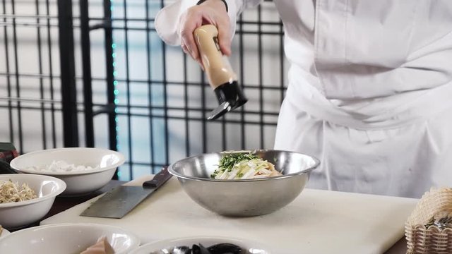 chef hands is pouring brown sause in a spring vegetable salad in a bowl in slow motion