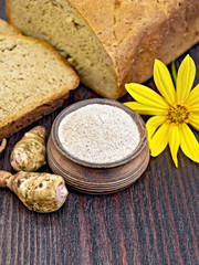 Fototapeta na wymiar Flour of Jerusalem artichoke in clay bowl with bread on board