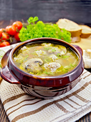 Soup with meatballs and mushrooms in clay bowl on napkin