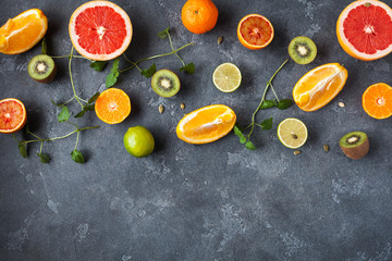 Colorful fresh fruit on dark background. Orange, tangerine, lime, kiwi, grapefruit. Fruit background. Summer food concept. Flat lay, top view, copy space
