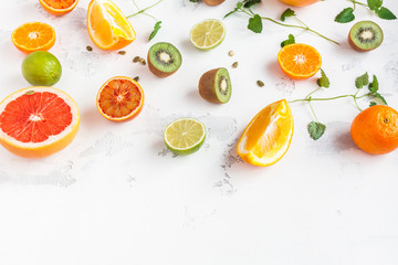 Colorful fresh fruit on white table. Orange, tangerine, lime, kiwi, grapefruit. Fruit background. Summer food concept. Top view, copy space