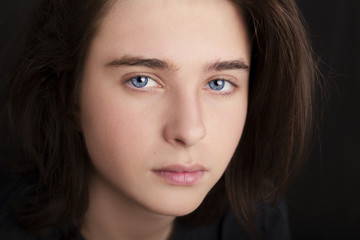 Naklejka premium A portrait of a handsome blue eyes teenager on dark background