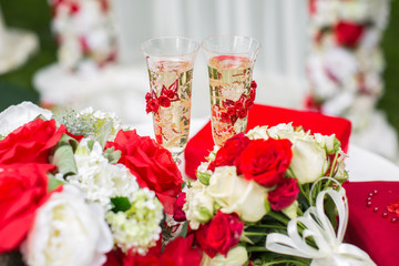 The champagne glasses. Wedding ceremony outdoors. Bouquet with red flowers.