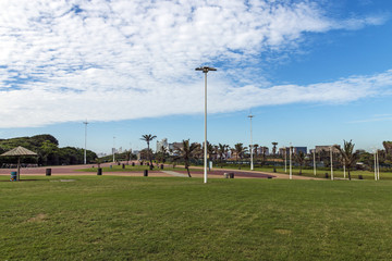 Green lawn paved promenade against city skyline in Durban