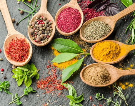 Assortment of colorful spices in the wooden spoons.