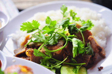 Vietnamese broken rice or com tam with fried chicken legs, pork and herbs