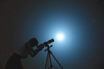 Girl looking at the stars through a telescope.