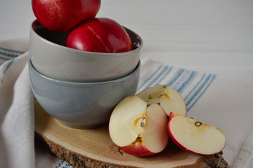 Red apples on gray ceramic plate plate on a wooden stand