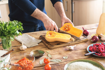 Male cooking dish of squash stuffed with rice and cranberries