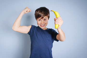 Starker Junge mit Banane zeigt seine Muskeln