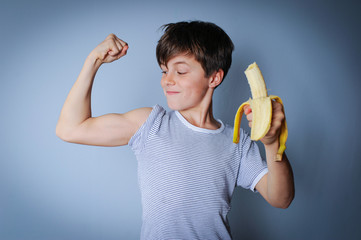 Starker Junge mit Banane zeigt seine Muskeln © photophonie