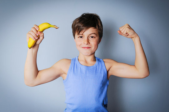 Starker Junge mit Banane zeigt seine Muskeln