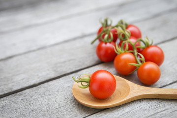 Closeup fresh tomato on wooden spoon over old wooden floor background