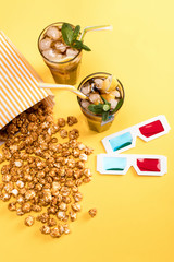 close up view of popcorn, iced tea and 3D glases on yellow, Movie time concept