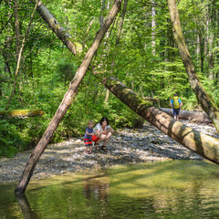 Mutter und Sohn erkunden das schattige Bachbett