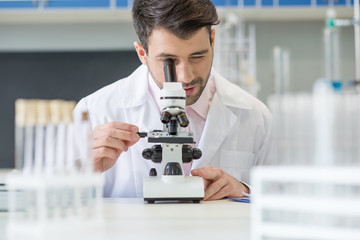 Man scientist in white coat working with microscope in lab