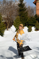 Woman throwing snow in the garden with a shovel